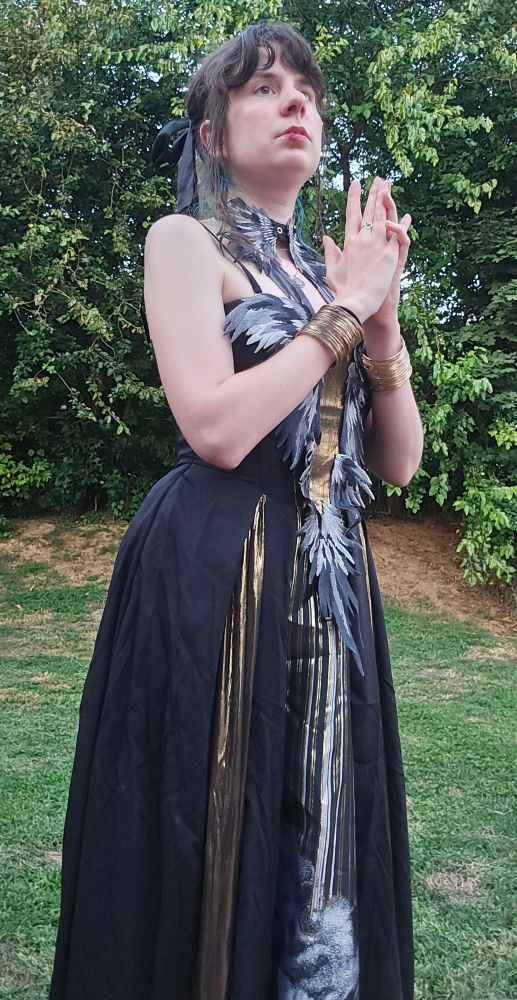 Jax in a black and gold dress with applique wings and Jacob's ladder motifs