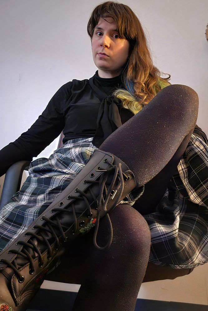 Jax looks into the camera and crosses one calf over her knee