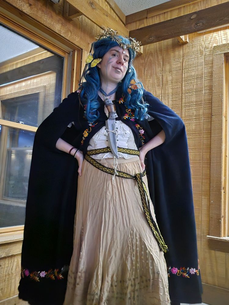 Jax in a green wig with a crown and a black cloak