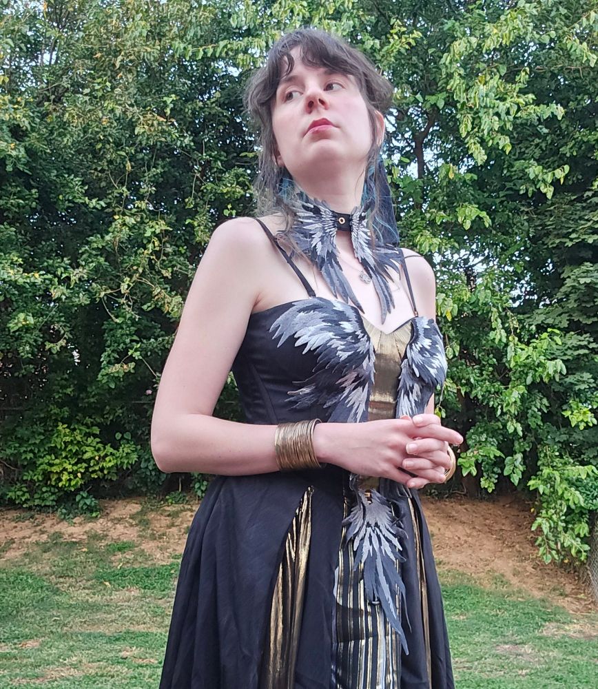 Jax in a black and gold dress with applique wings and Jacob's ladder motifs