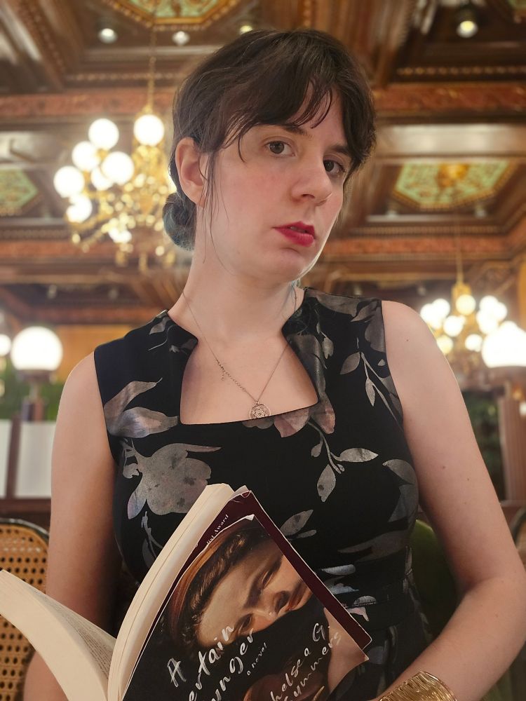 Jax in a Belle Epoque hotel bar with her book