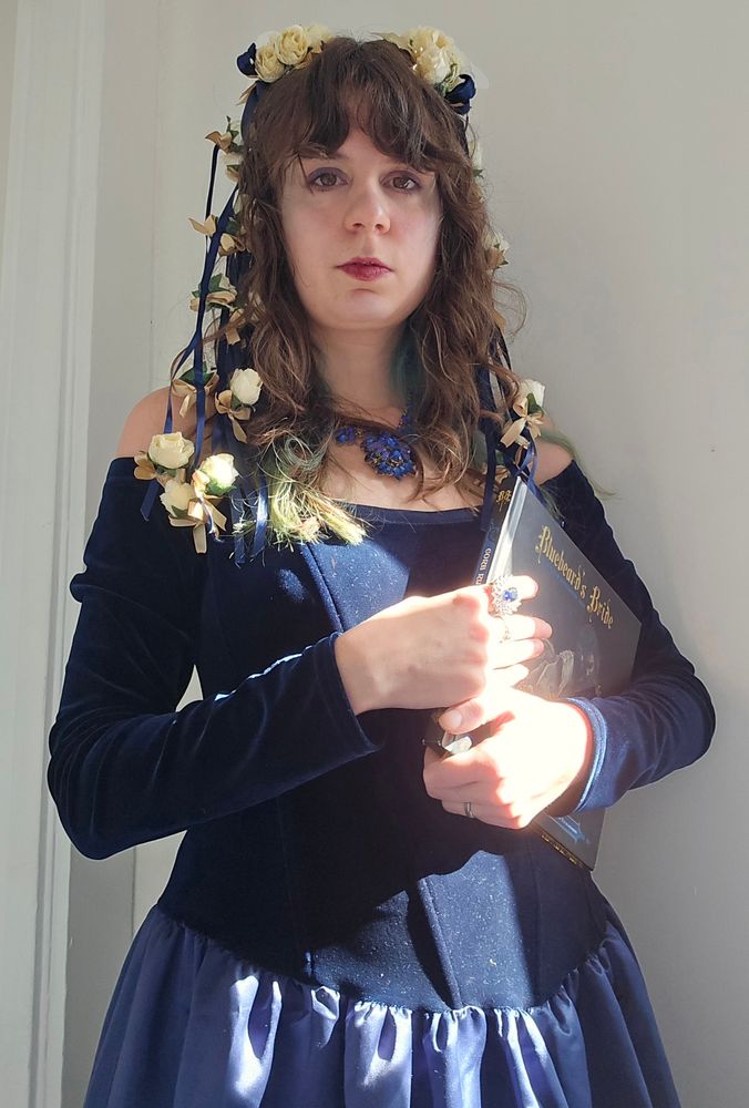 Jax in a dark blue ballgown with a blue statement necklace and blue and white floral hair falls