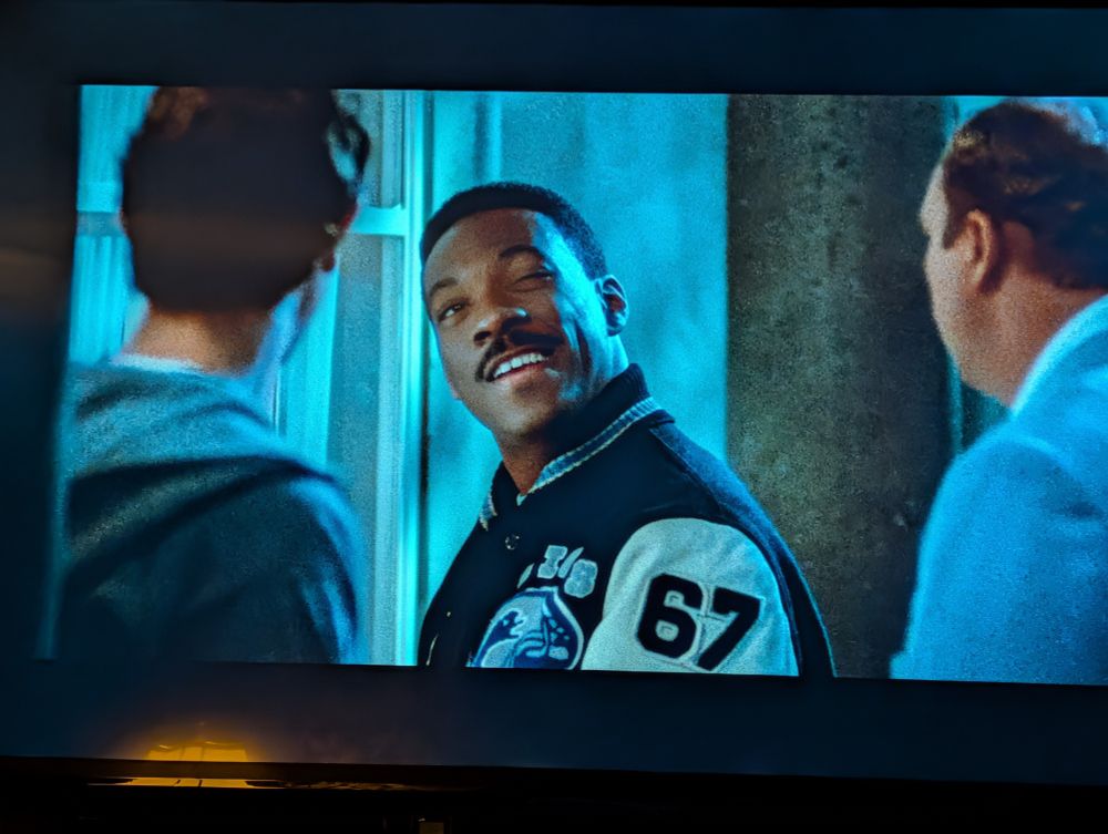 Eddie Murphy as Axel Foley in Beverly Hills Cop 2 wearing a letter jacket with 67 on the sleeve