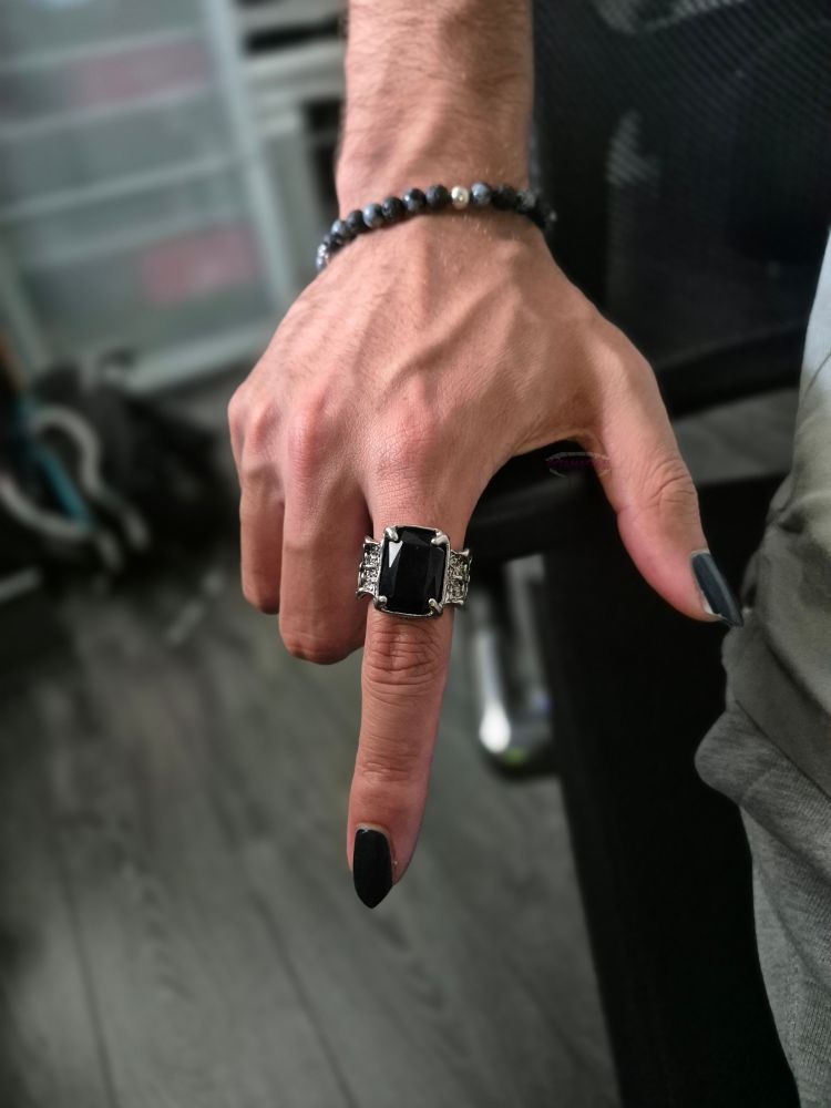 Handpic silver ring with black stone. Black and blue nailpolish on pointy nails. Pointing down. Veins. Beads bracelet
