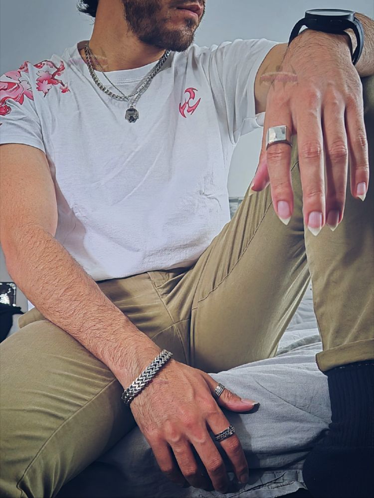 Outfitpic, khaki pants, white with pink shirt, one leg pulled up, hand over knee, other hand in lap, wearing silver rings, bracelet and necklace