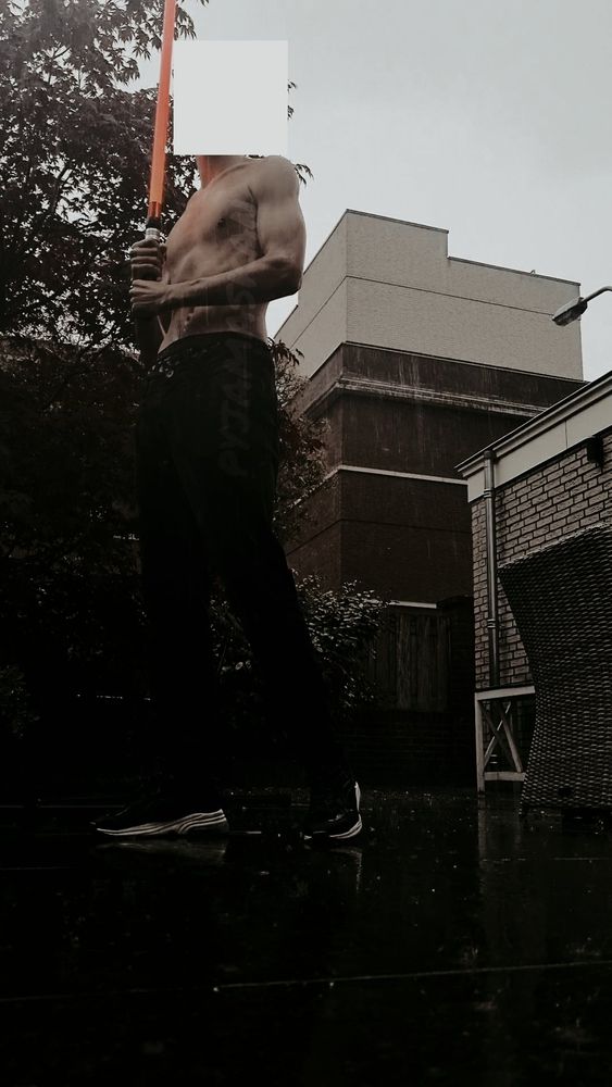 Shirtless in the rain holding red lightsaber