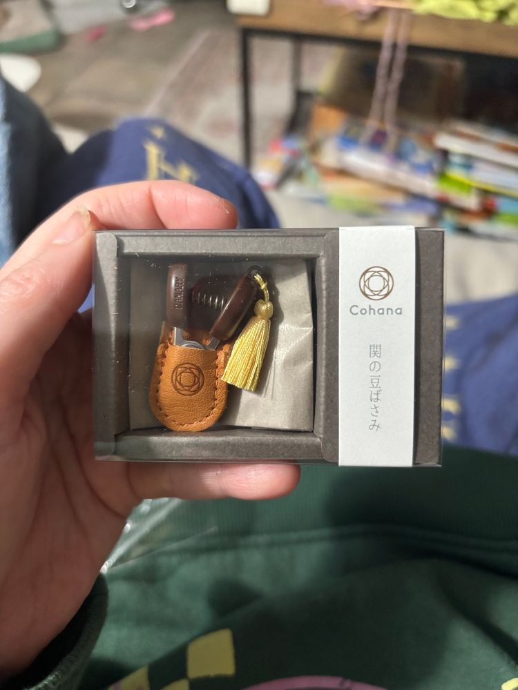 A hand holding Mini snips in a leather case and tassel from conhana