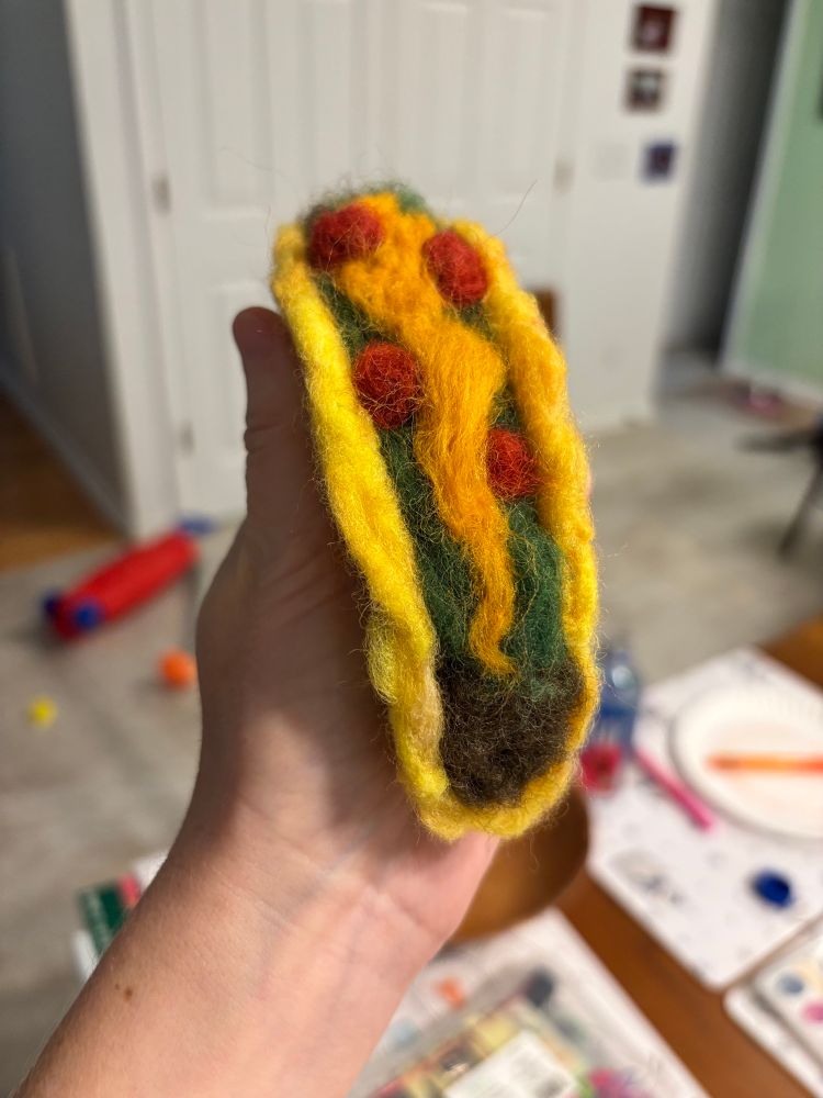 A big wool taco in someone’s hand. It’s needlefelting so it’s not edible. Crafters of bluesky
