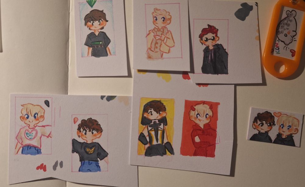 Several small drawings of the youtubers Dan and Phil and one of a seal in a plastik keychain 