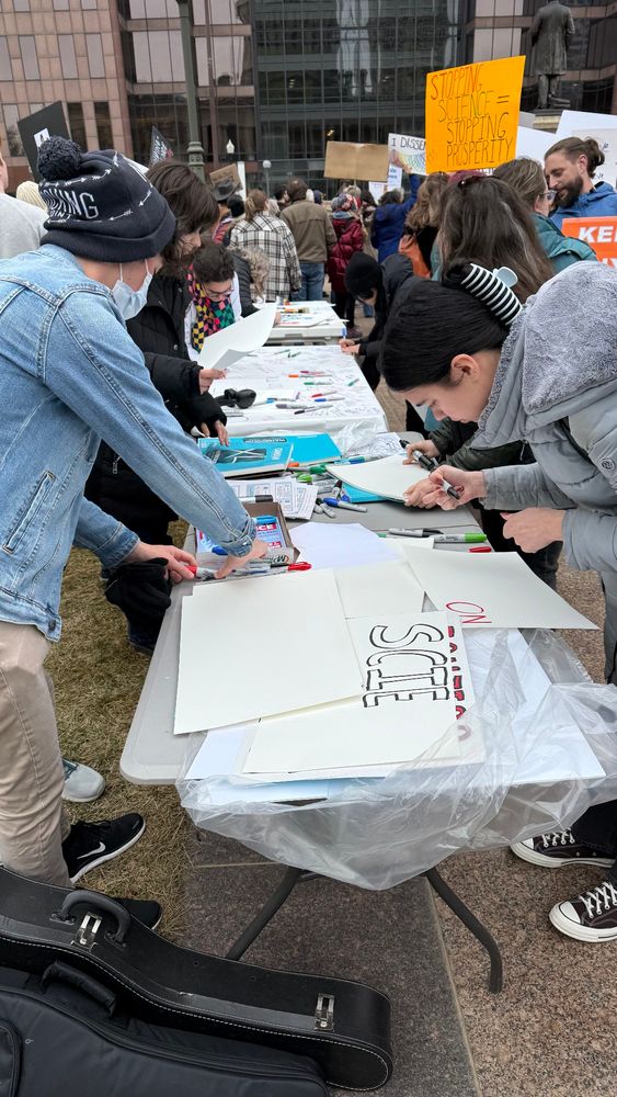 People gathering around a table, making posters 
