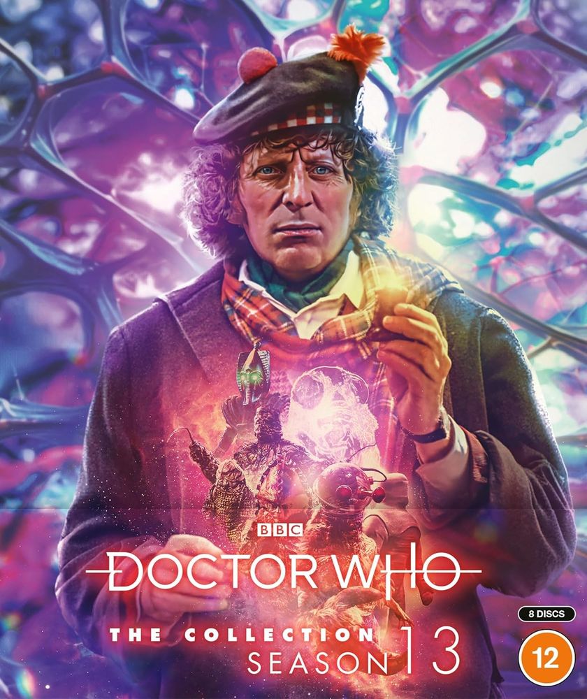 Doctor Who: The Collection – Season 13 Blu-ray cover: The Doctor (Tom Baker) with vivid blue eyes, Tam o’shanter and tartan scarf, holding a trilanic activator (you probably have one at home) and holding within a blaze of monsters, dark god Sutekh the Destroyer, glowing anti-matter beast from the edge of our Universe, walking plant human-Krynoid hybrid, rhino-faced Kraal, Egyptian Mummy-shaped robot, blobby bulbous suckered orange-red-green Zygon, Morbius (in composite body built to hold his brain with artificial eyes on stalks and huge claw) leading – as once he did the High Council of the Time Lords, then millions of fanatical followers when he dreamed the greatest dreams in history! All against a glistening indigo-blue honeycomb of translucent pinky-blue organic crystallography.