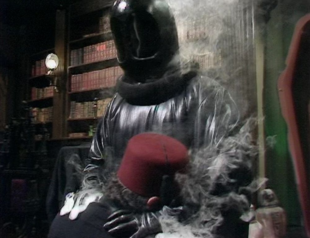 The black-robed, black-masked servant of Sutekh burn-strangles his discarded priest at the cliffhanger of Pyramids of Mars Part One 