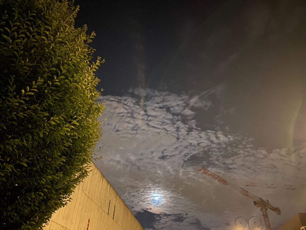 Ciel de nuit nuageux, un soir de pleine lune.
Un arbre à gauche, un bout de la caserne des pompiers de Puteaux au milieu et une grue à droite.