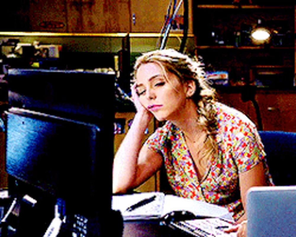 a woman is sitting at a desk with her head resting on her hand