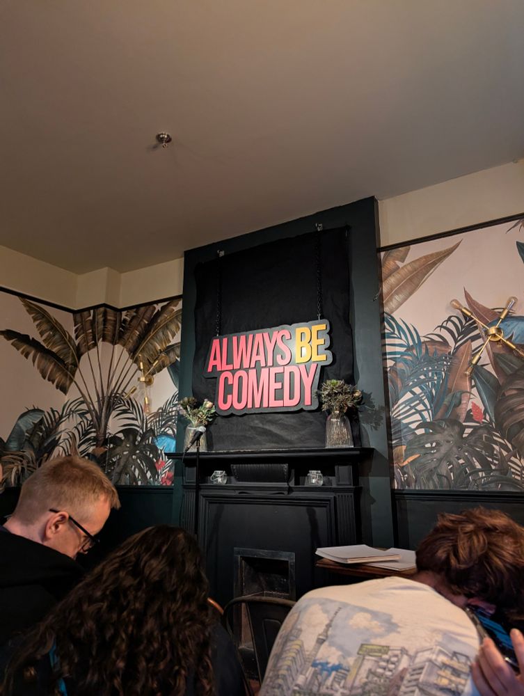 A spot-lit ‘Always Be Comedy' logo is visible on a wall above a fireplace at The Tommyfield pub in Kennington, London.