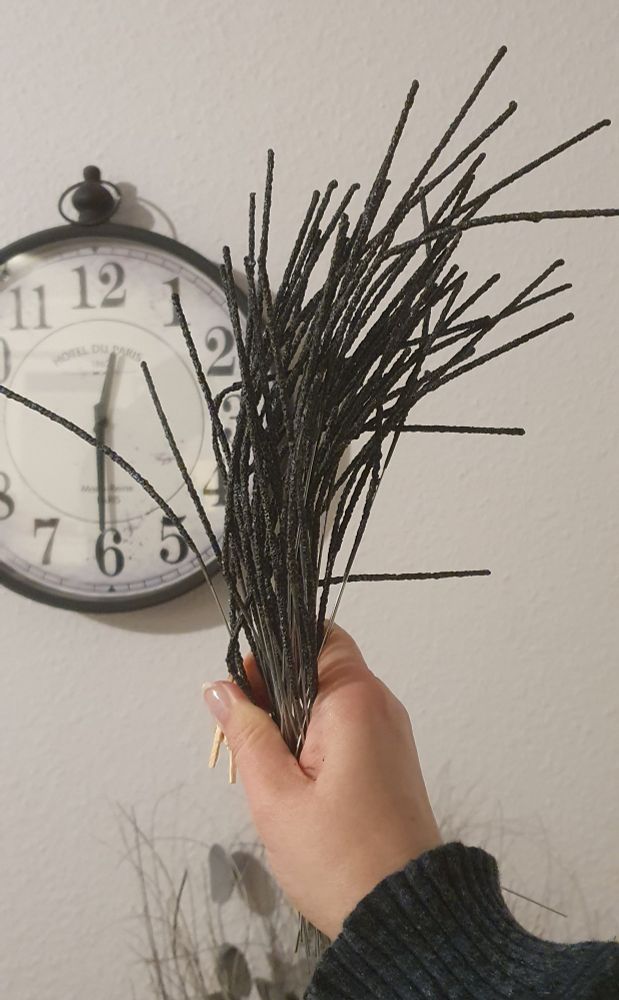 A hand holding a bouquet of burnt out sparklers in front of a watch showing 30 minutes past midnight.
