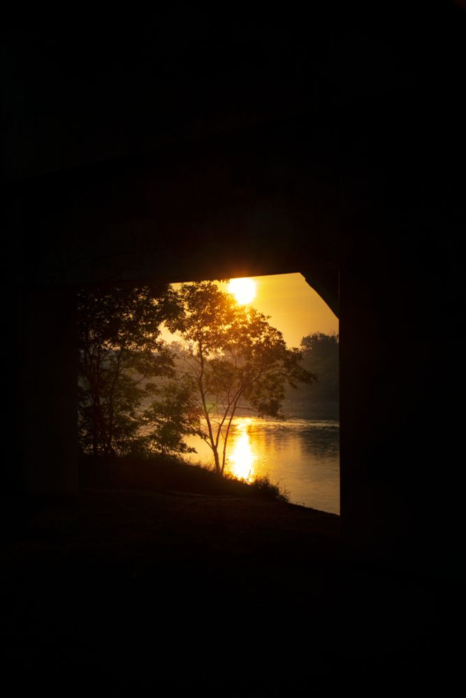 A june sunrise framed by a bridge. 