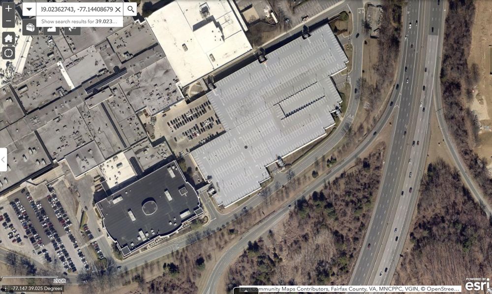 Satellite image of the east end of a large enclosed mall, with lots of surface and structured parking, next to a large interstate highway.