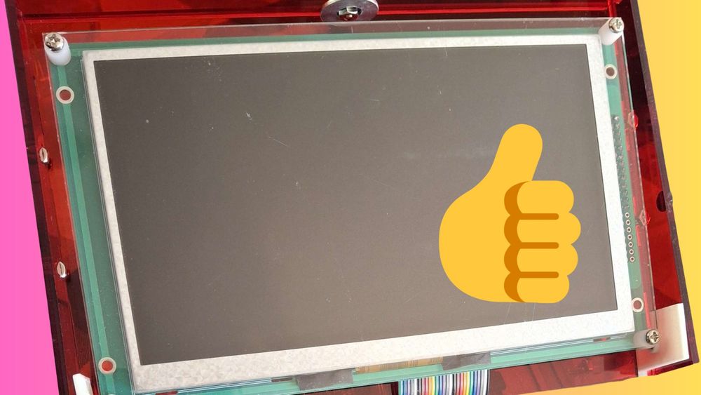 A picture of the Agape computer kit screen in a red case over a gradient that goes from pink to yellow. The screen is blank, except for a big thumbs-up emoji over the top of it.