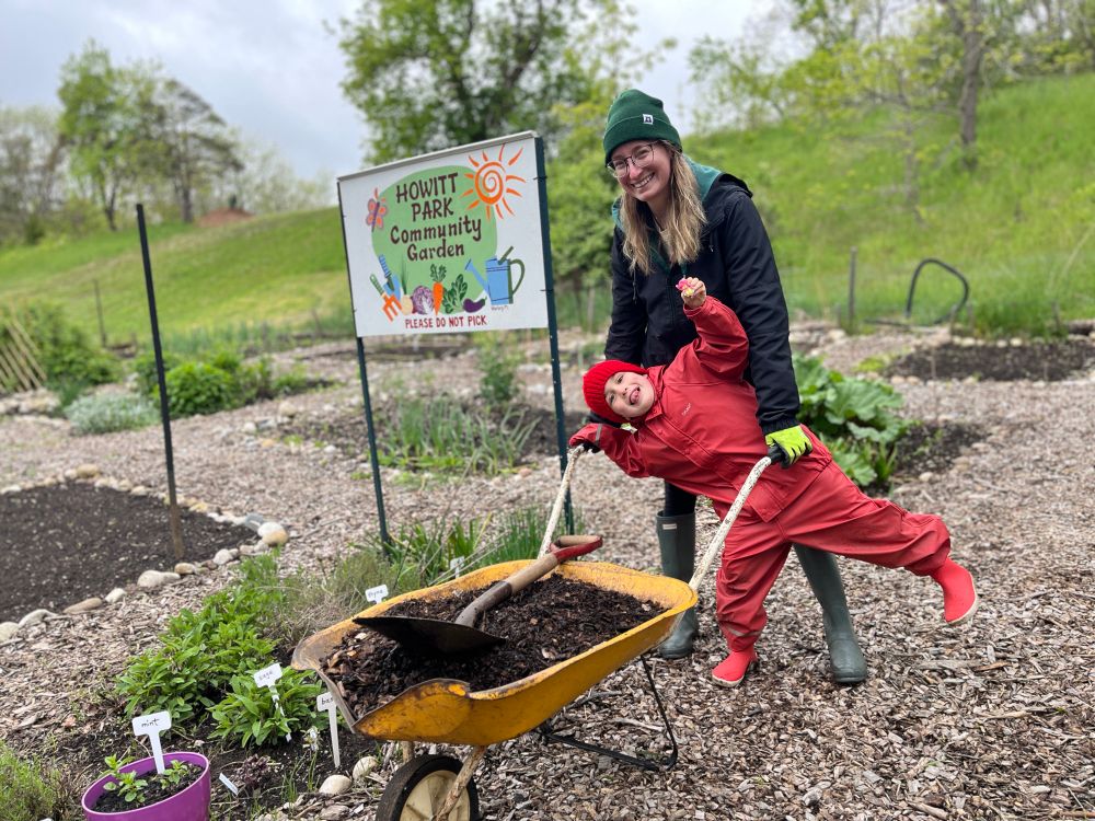 Young gardener having fun helping his mom spread compost in Howitt Park Community Garden.
