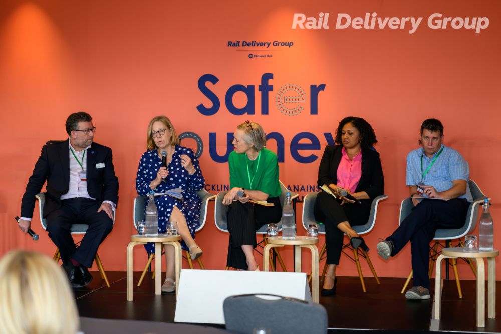 A picture of 5 people sitting on chairs on a panel- Ruth Cadbury is speaking into a microphone.
