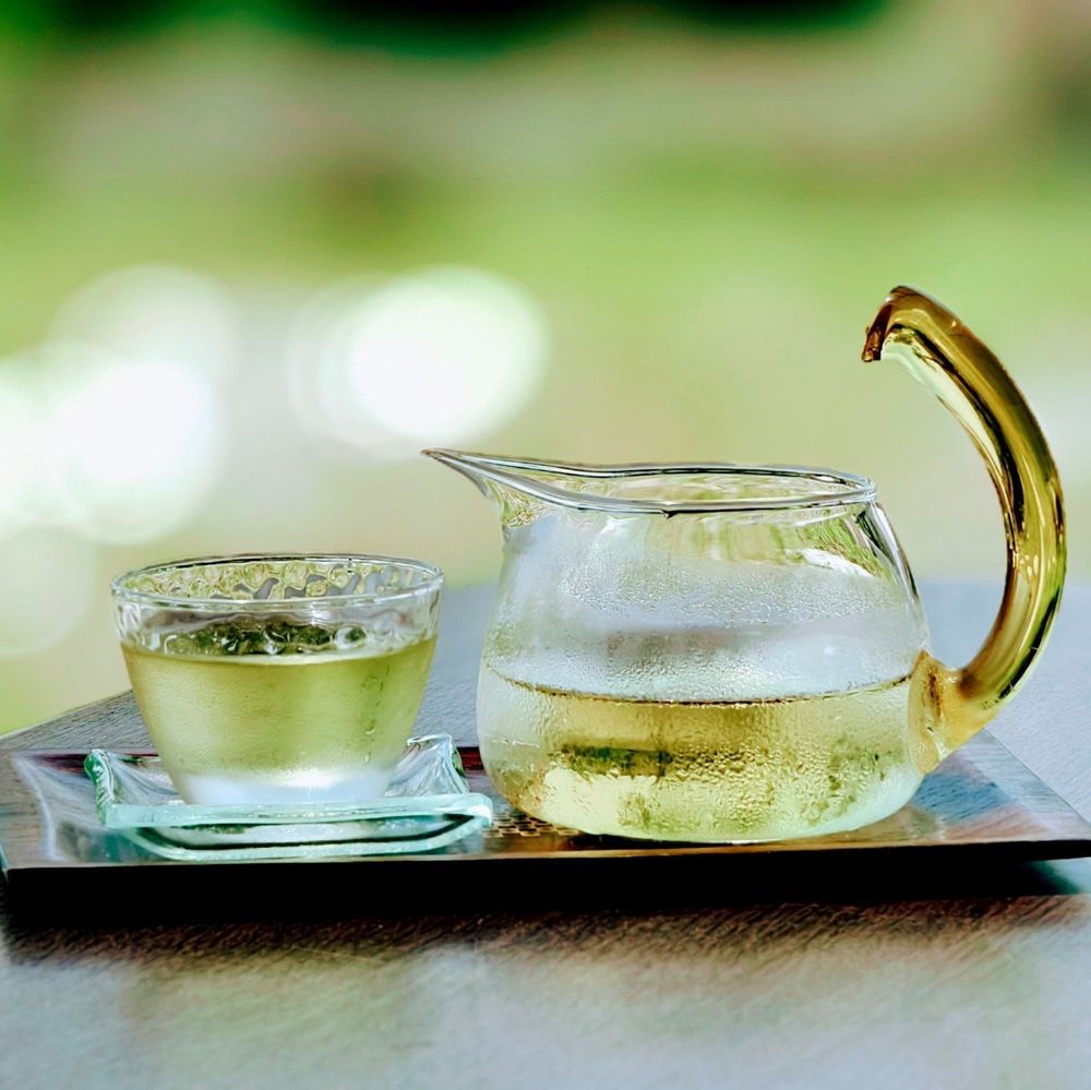 台湾茶の写真
左側にガラスのコップ、右側にガラスの茶海があり、木製のお盆に乗っています
中には金色の茶が入っています