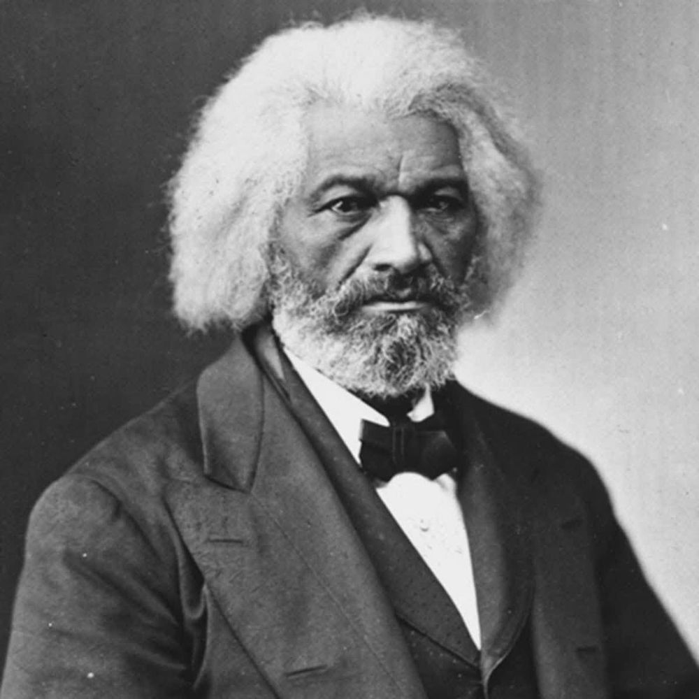 A black and white photo of Frederick Douglass, wearing a suit and bow tie 