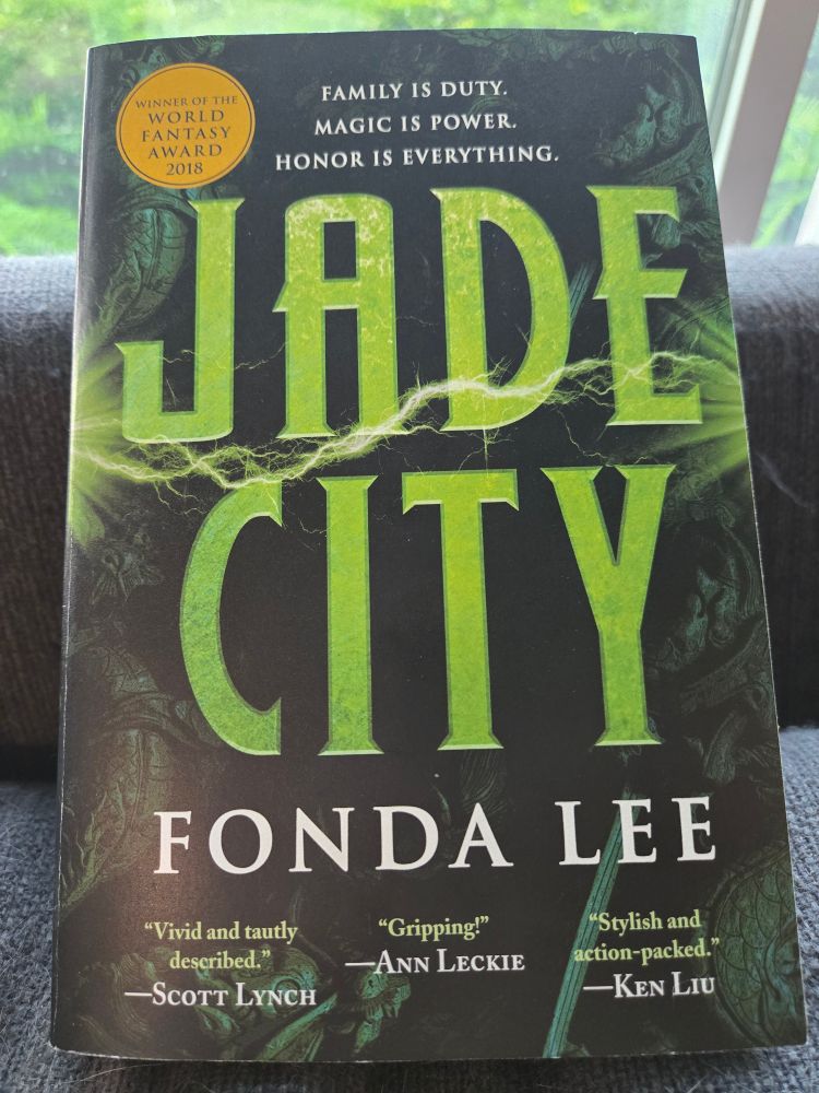 Dark green paperback book with the title Jade City it bright green