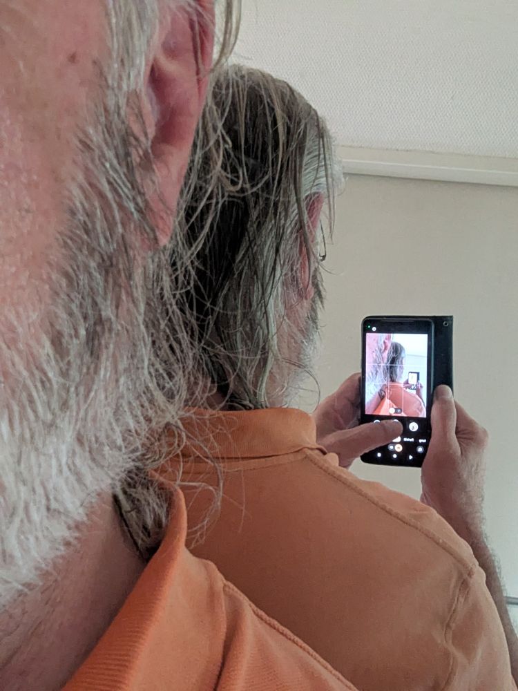 Man sieht in Spiegel meinen Hinterkopf und ein Handy, mit dem ich mich grade fotografiere, im Display erscheinen viele Duplikate der Szene