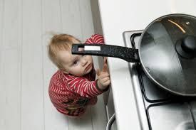 Young child reaching for hot pot on stove-top.