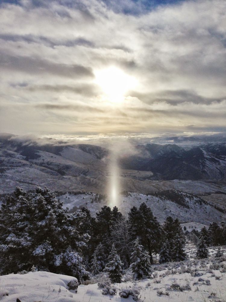 Panoramic photo my dad took in Montana while elk hunting in 2015. The sun is behind the clouds, and there's almost a lens flare effect that looks like a beam of light shining straight down to the ground.