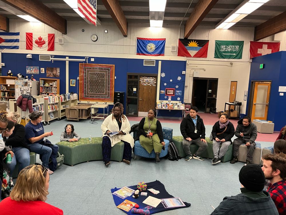 Community members seated in a circle talking in a school library.