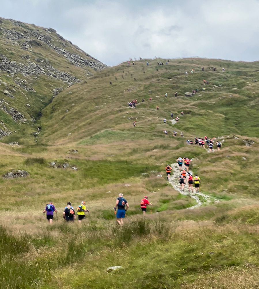 Lots of people running / hiking up a very steep hill!