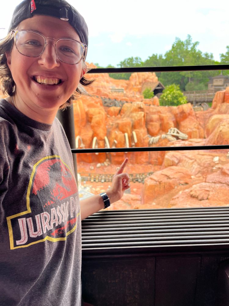 photo of Darby smiling and pointing to a dinosaur skeleton