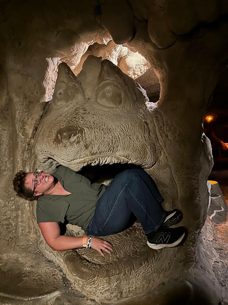 Rachel in the mouth of a large stone dragon at a museum, pretending to look scared