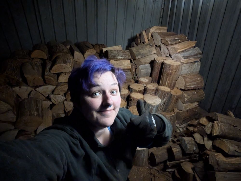 rad kneeling in front of her massive wood.. pile 😂