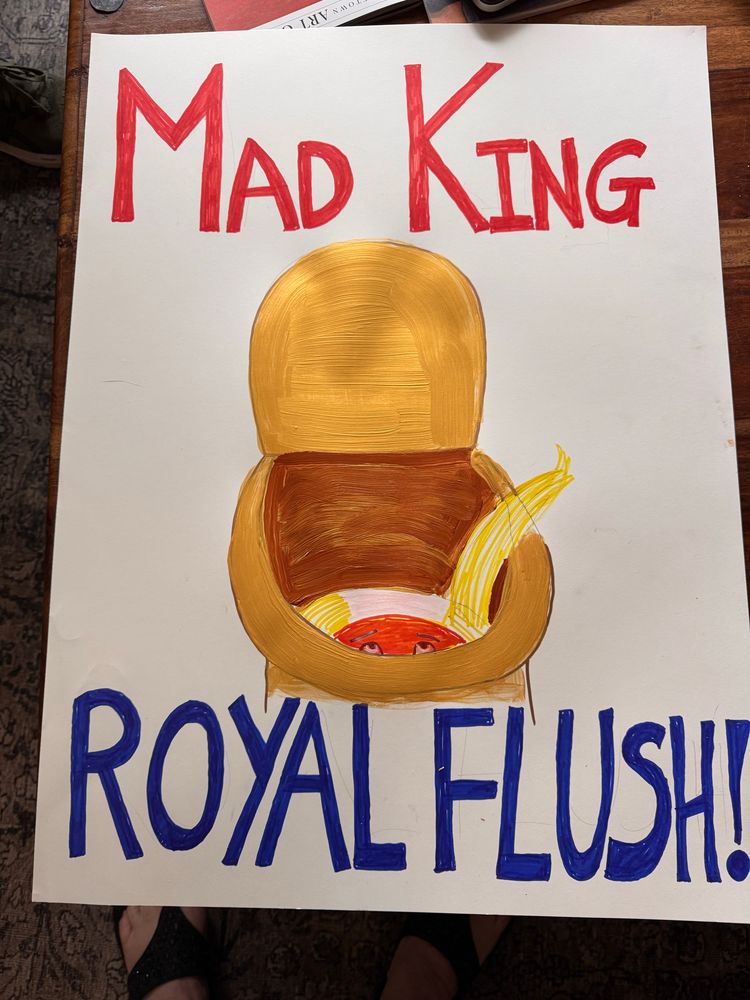 A very badly sharpie illustrated protest poster with horrible lettering which says “Mad King. Royal Flush!” Shows a golden loo. What’s in the gold toilet? Top of an orange face, weird combover, both going down the gurgler. Not pictured? This: 🥂