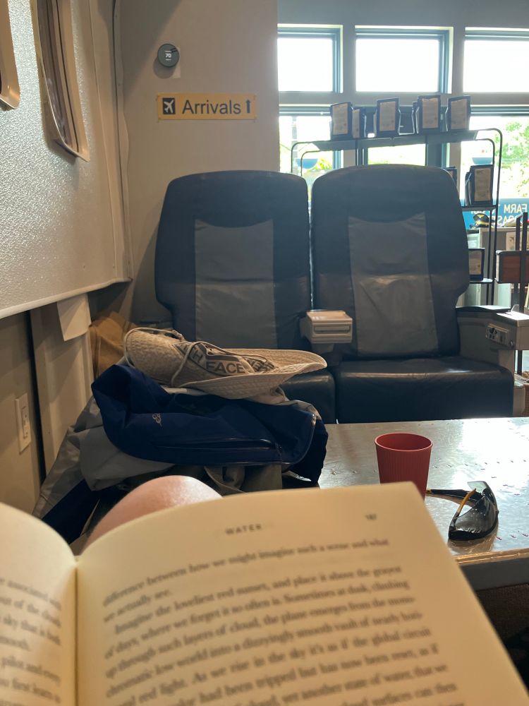 Image of a book in front of airplane seats and a table made of recycled fuselage 
