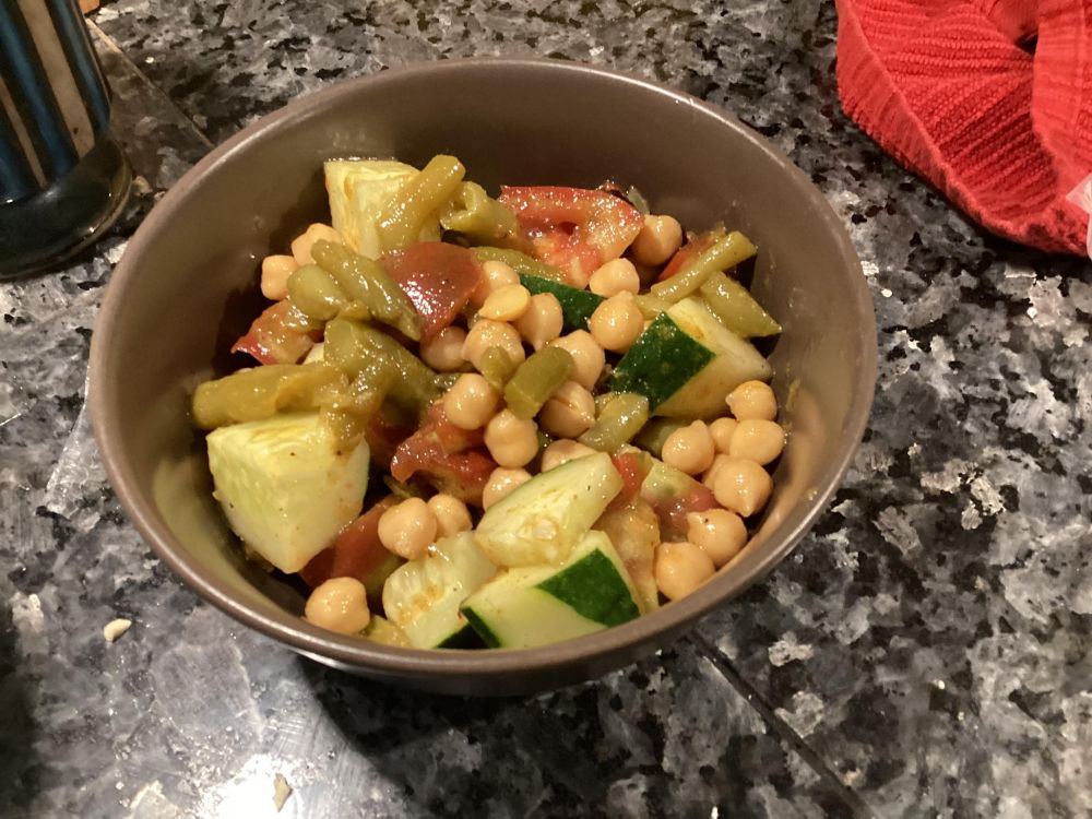 Image of a salad made from chickpeas, green beans, tomatoes, and cucumbers in a brown bowl
