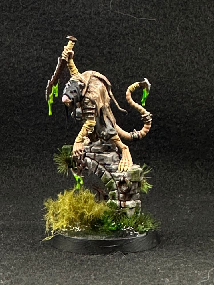 Skaven Deathmaster. It’s a rat man in muted browns and dark greys holding a poison dipped dagger. He’s crouched on a ruined bridge span above a swamp