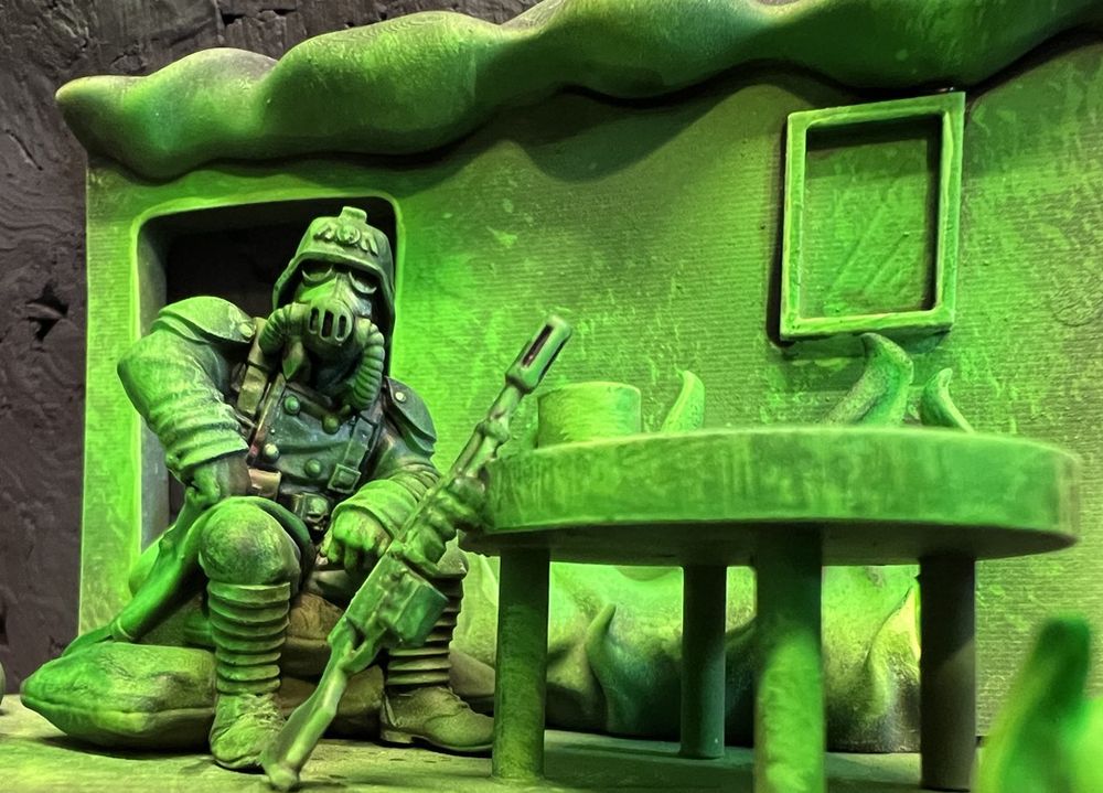 Kreig Guardsman sitting at a table in a room which appears to be on fire with green witch light