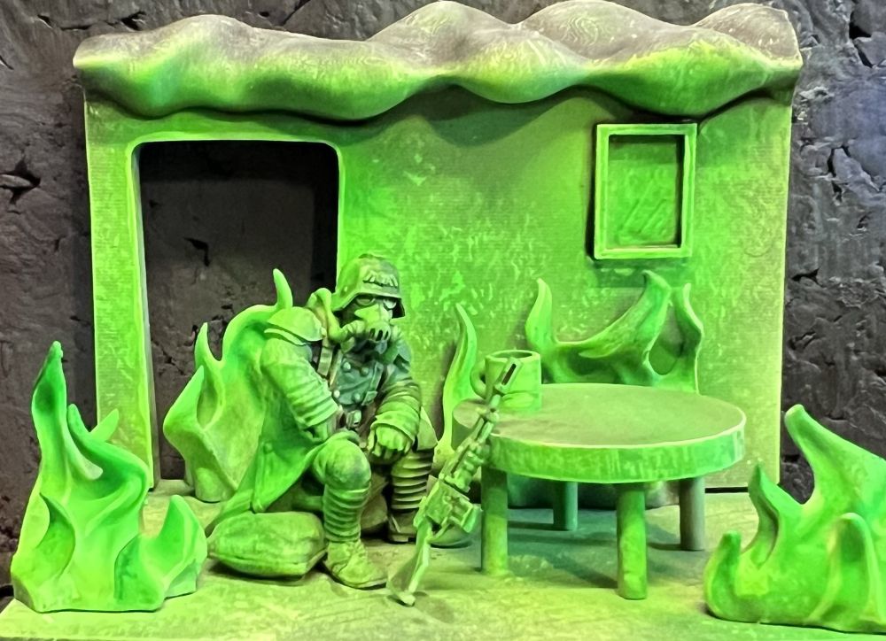Kreig Guardsman sitting at a table in a room which appears to be on fire with green witch light