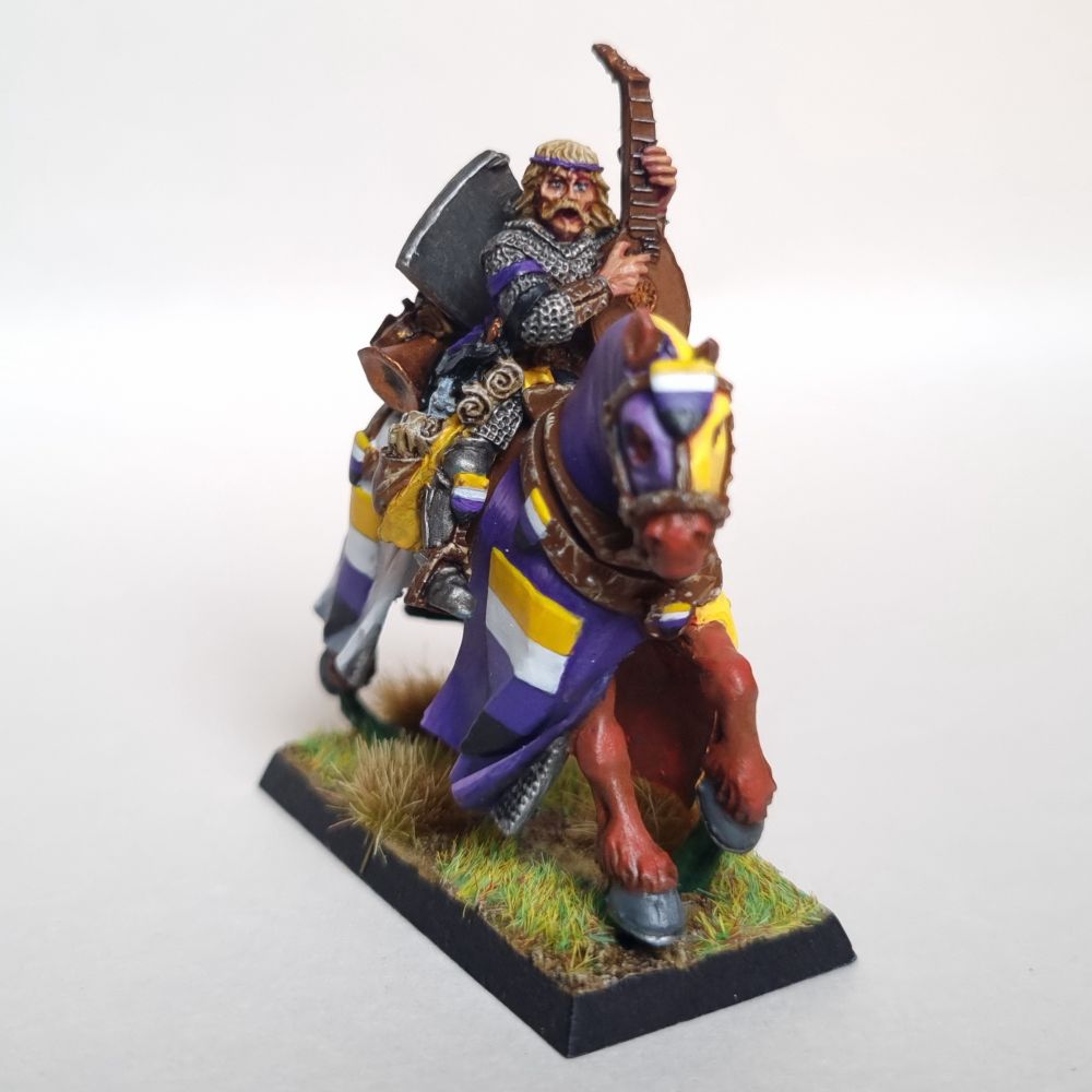 A Bretonnian questing knight musician. They wear the coat of arms and colour scheme of the non-binary flag.