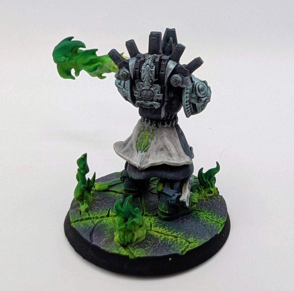 Blue-grey chaos space marine wielding a warp flamethrower shooting out a stream of green flame. They stand on a cracked purple surface with green flames erupting from the cracks.