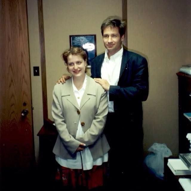 an old photo of Gillian Anderson and David Duchovny when they were just smol beans wearing ill-fitting clothes and looking dorky and cute