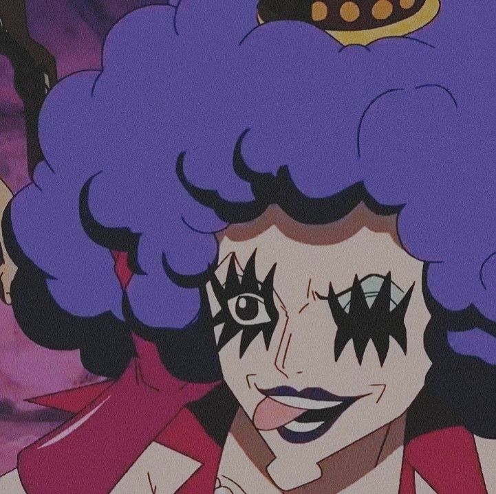 Pictured is a close up frame of Emporio Ivankov from One Piece. In there feminine form. They are winking their right eye with a wide grin, and their tongue sticking out to the left.