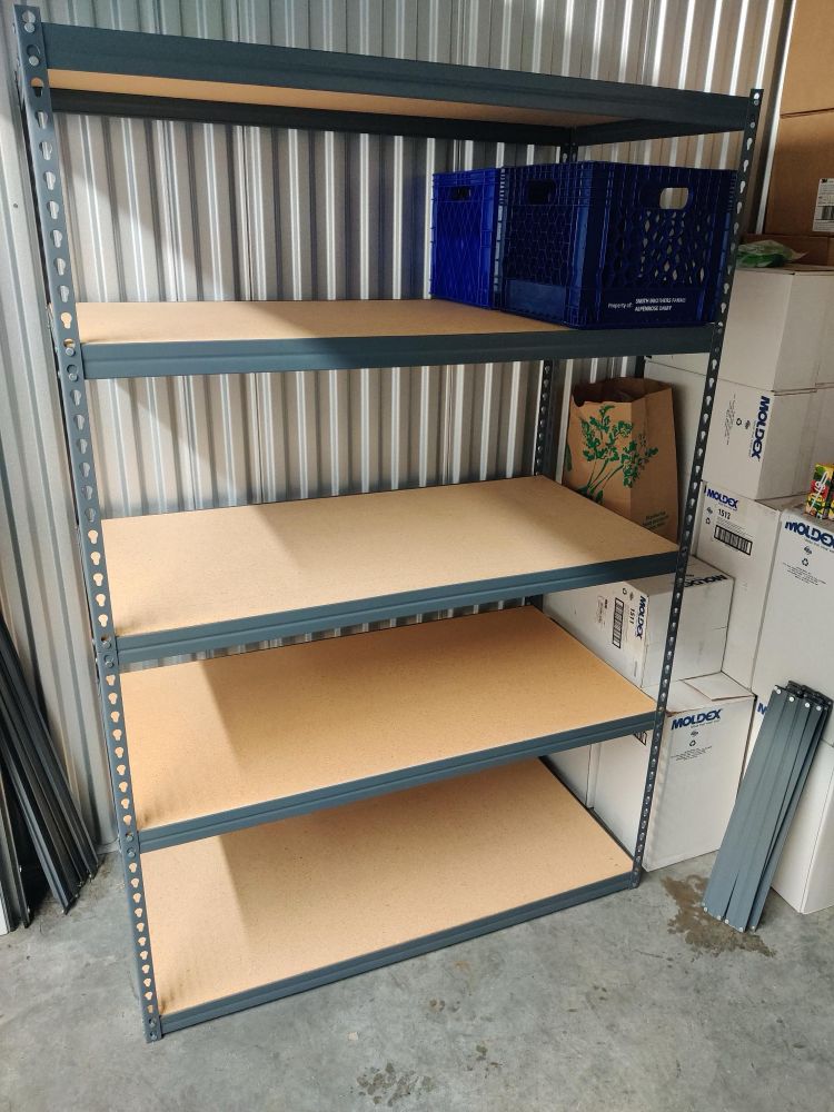 A photo of garage shelves with a lot of cases of masks standing next to it. 