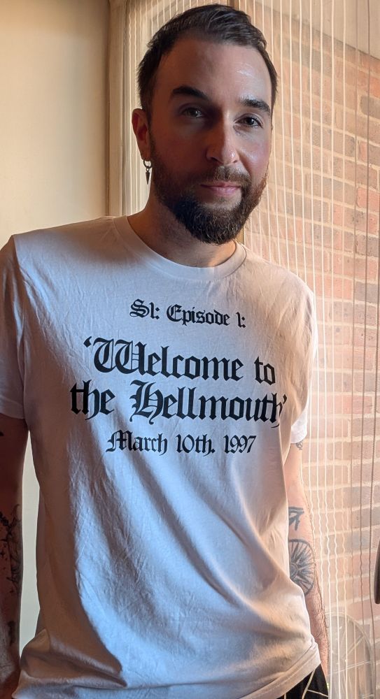 Tom is wearing a white t shirt that says "S1: Episode 1: 'Welcome to the Hellmouth' March 10th 1997, for the Buffy premiere. 