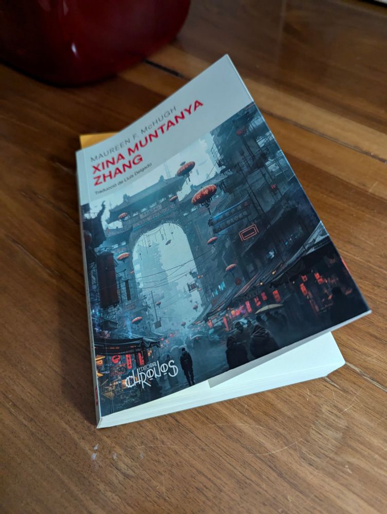 Fotografia d'un llibre ("Xina Muntanya Zhang" de Maureen F. McHugh) sobre una taula de fusta.