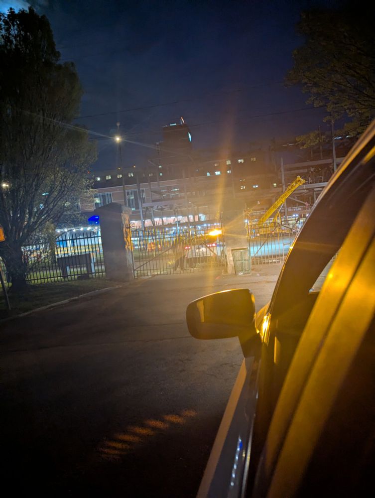 Closed gate of cemetery, with a public safety officer outside of it